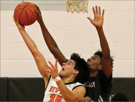  ?? STUART CAHILL — BOSTON HERALD ?? Lynn English’s Tyrese Melo Garcia blocks the shot of Newton North’s Jose Padilla on Tuesday, but NN collected a 52-38 state tournament victory.