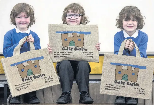  ?? PHIL REES ?? Tesco Bridgend shopping bag design winner Will Evans, five, holding his winning design with his brothers Charlie, seven, and Harry, six