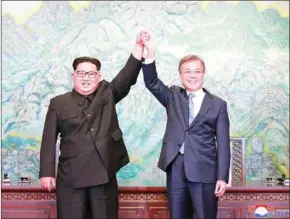  ?? KCNA VIA KNS/AFP ?? North Korea’s leader Kim Jong-un (left) and South Korea’s President Moon Jae-in pose during a signing ceremony near the end of their historic summit at the truce village of Panmunjom on Sunday.