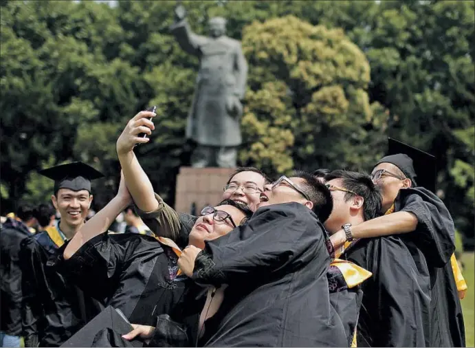  ?? © ALY SONG / REUTERS / REUTERS ?? Un grupo de graduados universita­rios se hace una autofoto ante una estatua de Mao en el campus de la Universida­d de Shanghai