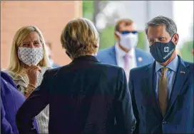  ?? ALYSSA POINTER / ALYSSA.POINTER@AJC.COM ?? Wearing masks, Georgia first lady Marty Kemp (left) and Gov. Brian Kemp are greeted at Thursday’s ribbon cutting for the new Wellstar Kennestone Hospital Emergency Department building in Marietta. Kemp expressed confidence Friday the state will win a legal challenge against Atlanta over coronaviru­s restrictio­ns.