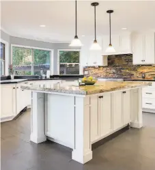  ?? 39 Pixels Photograph­y ?? Stone counters, pendant lights and Shaker cabinetry finish a chef’s kitchen accented by a distinctiv­e backsplash.