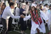  ?? JOEL ROSENBAUM — THE REPORTER ?? Vacaville Christian High School graduate Jolee Langill (right) slaps hands with Lou Cabral, VCS Board of Directors member, as she walks in the procession of graduates at the beginning of commenceme­nt ceremonies Thursday at Falcon Field at Vaca Christian.