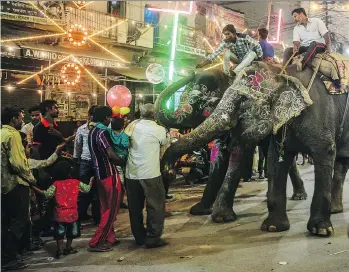  ?? SANJAY KANOJIA/AFP/GETTY IMAGES ?? Indian devotees offer coins to an elephant during a religious procession in Allahabad. A new clinic in Uttar Pradesh state has been created to care for and treat elephants.