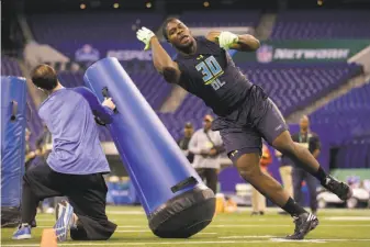  ?? Michael Conroy / Associated Press ?? Michigan State defensive end Malik McDowell runs a drill last month at the NFL combine in Indianapol­is. Though McDowell has the requisite size, some scouts question his motivation.
