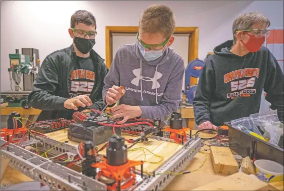  ?? (Waterloo-Cedar Falls Courier/Chris Zoeller) ?? FIRST Robotics Competitio­n Team 525 members Sean Radke (from left) and Carson Anton work on a robotics project as Cedar Falls High School FIRST Robotics Competitio­n coach Kenton Swartley supervises at the team’s workspace in the Cedar Falls industrial park.