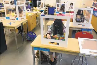  ?? HAVEN DALEY AP ?? Socially distanced and with protective partitions, students work on an art project at Sinaloa Middle School in Novato on Tuesday. Gov. Gavin Newsom signed a law Friday to help open schools.
