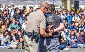  ?? Brennon Dixson/The Signal ?? During a demonstrat­ion, a California Highway Patrol officer from the Newhall Station takes a student into custody to signify the ramificati­ons of driving distracted or under the influence of controlled substances.