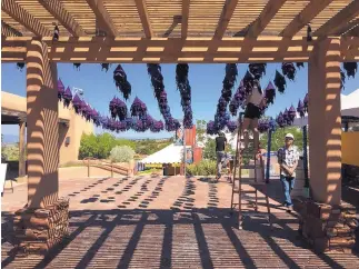  ?? MORGAN LEE/ASSOCIATED PRESS ?? Workers hang lantern decoration­s Monday at the entrance to the Internatio­nal Folk Art Market in Santa Fe. The bazaar is expanding to highlight innovation and high fashion within folk art traditions.