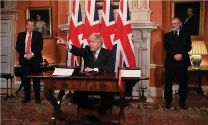  ?? Photograph: Leon Neal/Getty Images ?? The UK chief negotiator, David Frost, left, and the British ambassador to the EU, Tim Barrow, flank Boris Johnson as he signs the Brexit deal on Wednesday.