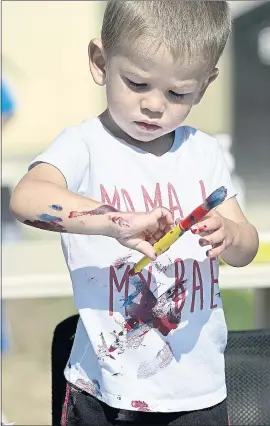  ?? JOEL ROSENBAUM — THE REPORTER ?? Eli Obert, 1 1/2 of Suisun City, pauses to study his paint-covered arm as he works on an art project Wednesday during “Big Messy Art Day” at the Suisun City Library. Young artists had the opportunit­y to make paintings, collages, and paper bag hand puppets during the event that one of the first large group activities held at the Suisun City branch after they were all canceled last year due to the pandemic.