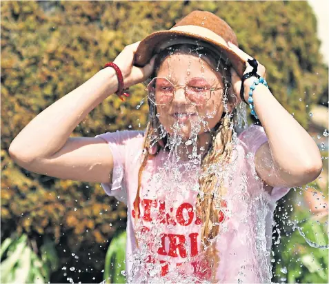 ??  ?? Flower Sykes, 14, from Cornwall, tips a hat filled with water over her head to cool down at the Glastonbur­y Festival yesterday