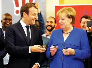  ??  ?? French President Emmanuel Macron offers a soft ball to German Chancellor Angela Merkel, as they visit the Franco-German Youth Office in Paris, on Thursday. (Reuters)