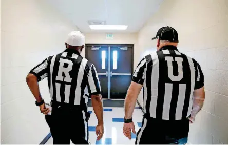  ?? [PHOTOS BY BRYAN TERRY, THE OKLAHOMAN] ?? Officials Harold Hill, left, and Glen Williams leave the locker room on their way to the field before officiatin­g Edmond Memorial and Westmoore last month.