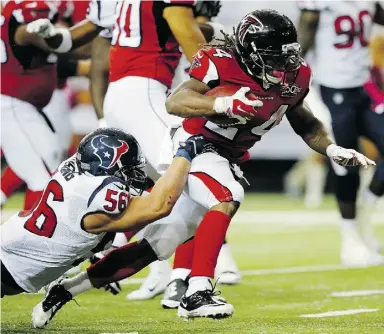 ?? Kevin C. Cox / Getty Images ?? Devonta Freeman scampers for one of his touchdowns Sunday against Texans linebacker
Brian Cushing in the second half of their NFL game at the Georgia Dome.