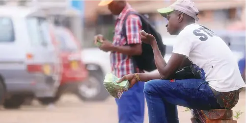  ??  ?? A forex dealer brandishes wads of $2 and $5 notes in Harare. The Zimdollar has continued losing value against stronger currencies like the rand and the United States dollar.