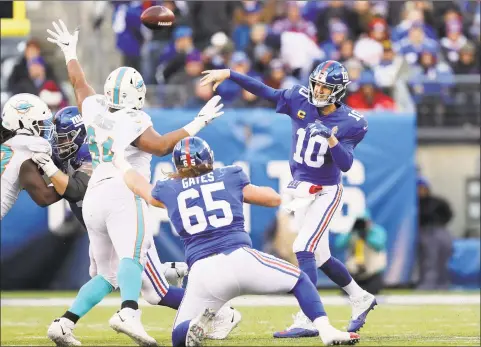  ?? Elsa / Getty Images ?? Eli Manning (10) of the New York Giants passes under pressure from Christian Wilkins (94) of the Miami Dolphins as Nick Gates (65) of the New York Giants helps block at MetLife Stadium on Sunday in East Rutherford, N.J.