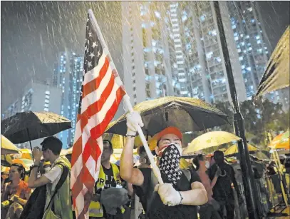  ?? Vincent Yu The Associated Press ?? A protester waves a U.S. flag as hundreds gather Tuesday outside a police station in Hong Kong. Protesters clashed with police again.