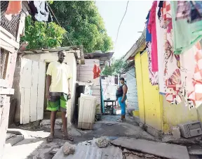  ?? PHOTOS BY RICARDO MAKYN/MULTIMEDIA PHOTO EDITOR ?? Brian Martin (left), president of the Interim Committee of the Maxfield Park community (Frog City), showing conditions inside a yard in the community while a resident looks on.