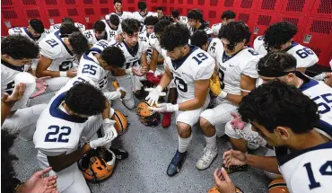  ?? PAUL SANCYA/AP ?? Crestwood High School football player Adam Berry (19) leads a Muslim prayer before a game in Melvindale, Mich., on Sept. 23. At Crestwood High School, where most of the football team is Muslim, the entire team gathers before practices and games to pray on one knee.