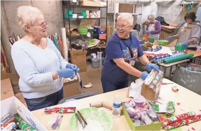  ?? MARK HOFFMAN/MILWAUKEE JOURNAL SENTINEL ?? Volunteers Carol Weaver (left) and Jan Nosse share a laugh while wrapping boxes that will be used for enrichment gifts at the Milwaukee County Zoo.