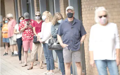  ??  ?? VOTERS line up at a local precinct during the in-person early voting.