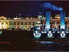  ?? AP ?? Tug boats tow the Aurora Cruiser past the Winter Palace along the Neva River in St. Petersburg early yesterday.