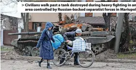  ?? ?? Civilians walk past a tank destroyed during heavy fighting in an area controlled by Russian-backed separatist forces in Mariupol