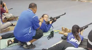  ?? Photo courtesy of Lawrence Pagaduan ?? Maui High coach Lawrence Pagaduan talks with Taylor McCary as she shoots in the prone position.