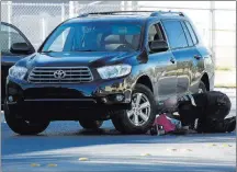  ??  ?? An investigat­or checks underneath a vehicle after the death of a 9-year-old boy riding a bicycle.