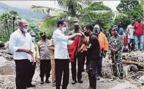  ?? AFP PIC ?? A handout photo taken and released yesterday by the Indonesian Presidenti­al Palace showing President Joko Widodo giving his jacket to a flood survivor on Lembata Island.