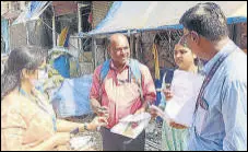  ?? HT PHOTO ?? BMC’s community mobiliser Vinod Rathod (pink shirt) discusses list of patients with WHO officials.