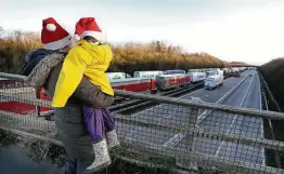  ?? KirstyWigg­lesworth / Associated Press ?? A mother and child look at the line of trucks parked on the M20 highway on Christmas Day as U.K.-France travel was restricted in response to the virus.