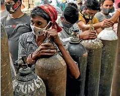  ?? AP ?? Relatives of Covid patients wait to refill oxygen cylinders in New Delhi, where queues stretch everywhere, says Puranam.