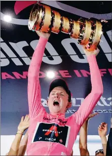  ?? AP ?? Britain’s Tao Geoghegan Hart hoists the trophy after winning the Giro d'Italia in Milan on Sunday.