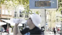  ?? JOSEP GARCÍA ?? Un hombre bebe agua ante un termómetro que marca los 35 grados.
