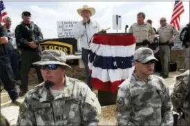  ?? LAS VEGAS REVIEW-JOURNAL VIA AP ?? In this 2014 photo rancher Cliven Bundy, top center, addresses his supporters along side Clark County Sheriff Doug Gillespie, right, while being guarded by self-described militia members in the foreground.