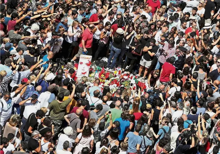  ?? — Reuters ?? Showing solidarity: People gathering around flowers and candles placed to honour the victims of the van attack at Las Ramblas in Barcelona.