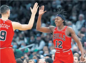  ?? MICHAEL DWYER/AP ?? Chicago Bulls guard Ayo Dosunmu (12) celebrates with Nikola Vucevic (9) during the second half against the Boston Celtics on Monday.