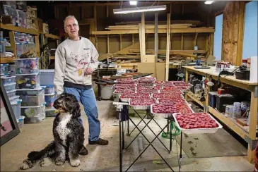  ?? STEVE SCHAEFER / SPECIAL TO THE AJC ?? Shulman, with his dog Juno, talks about the process of painting the 2,700 corks for one of his projects at his home in Sandy Springs. Shulman said he isn’t sure where his ideas come from; he just likes working with different materials and textures.