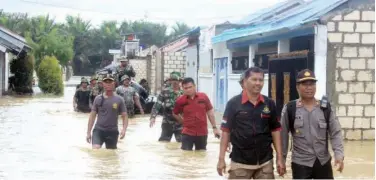  ?? Associated Press ?? ↑ Indonesian police and soldiers search for residents who need assistance in a flooded neighbourh­ood in Sentani on Monday.