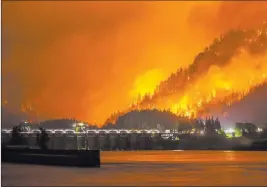  ?? Tristan Fortsch ?? The Associated Press A wildfire is seen Monday near Stevenson Wash., across the Columbia River, burning in the Columbia River Gorge above the Bonneville Dam near Cascade Locks, Ore.