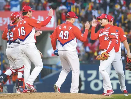  ?? Yonhap ?? The Kia Tigers players celebrate after winning Game 4 of the Korean Series at the Jamsil Baseball Stadium in Seoul, Sunday.