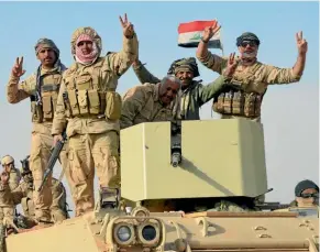  ??  ?? Iraqi soldiers flash victory signs after they recaptured Rawa, the last remaining town under Islamic State control.