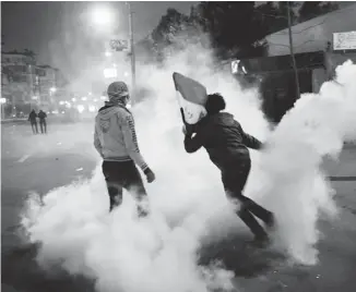  ?? ED GILES/GETTY IMAGES ?? An Egyptian protester throws a tear-gas canister fired by security forces toward riot police Friday. Fewer than one per cent of Cairo residents have shown up for anti-government protests, writes Matthew Fisher.