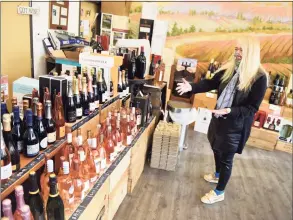  ?? Tyler Sizemore / Hearst Connecticu­t Media ?? Store owner Theresa Rogers points out a large selection of champagne available at Harbor Point Wines & Spirits at 130 Washington Blvd. in Stamford on Wednesday. Some of the holiday best-sellers at local wine and spirits store have been champagne, two for $20 wine, bourbon, IPA beers and sampler gift sets.