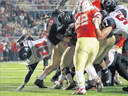  ?? Photograph­s by Gina Ferazzi Los Angeles Times ?? CORONA CENTENNIAL’S J.J. Taylor finds his way through the pile for one of his three touchdowns against Orange Lutheran.