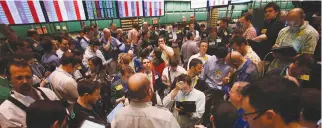  ??  ?? TRADERS GESTURE while working in the crude oil and natural gas options pit on the floor of the New York Mercantile Exchange, March 7, 2011.