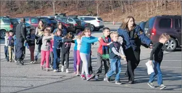  ?? Shannon Hicks
Newtown Bee ?? CONNECTICU­T POLICE lead students from Sandy Hook Elementary School. The Dec. 14, 2012, shooting left 26 people at the school dead and spurred efforts by the Obama administra­tion to tighten gun restrictio­ns.