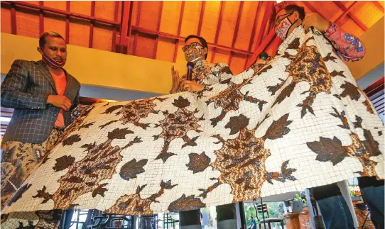  ?? DIPTA WAHYU/JAWA POS ?? WARISAN: Bupati Pamekasan Baddrud Tamam (tengah) menjelaska­n batik penyu yang telah berusia 120 tahun dalam pameran Mahakarya Batik Pamekasan di Hotel Bumi kemarin.